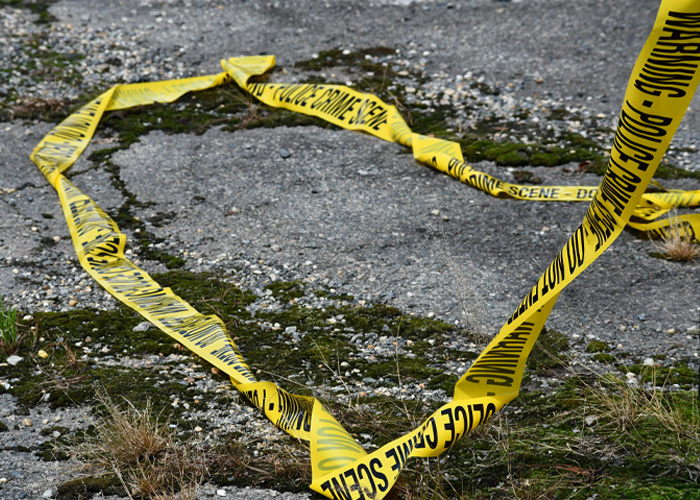 Yellow police crime scene tape on mossy ground at a French crime scene