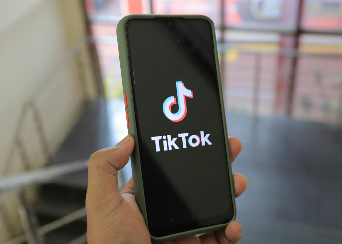 Hand holding smartphone displaying TikTok app logo on screen