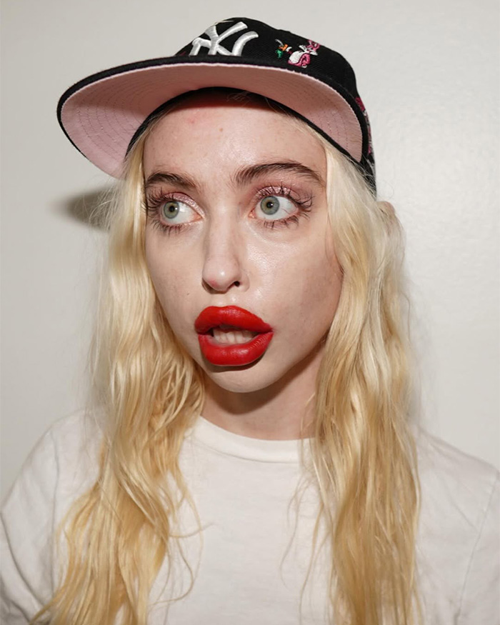 Chloe Cherry with large lips and red lipstick wearing a cap