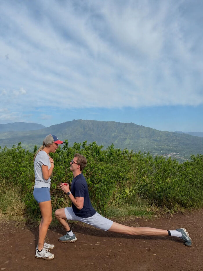 A man proposes to a woman on a mountain, creating a viral proposal pic. His long leg stretch is notable.