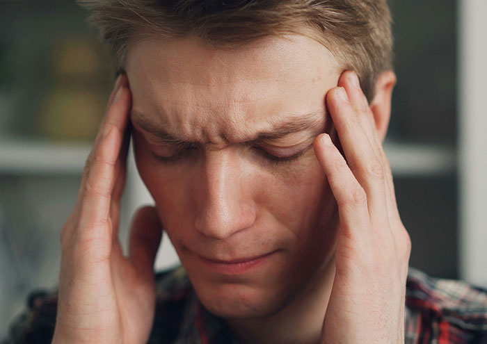 Man holding temples in stress during close encounter with passing away experience