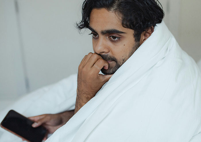 Thoughtful man wrapped in white blanket reflecting on passing away experience