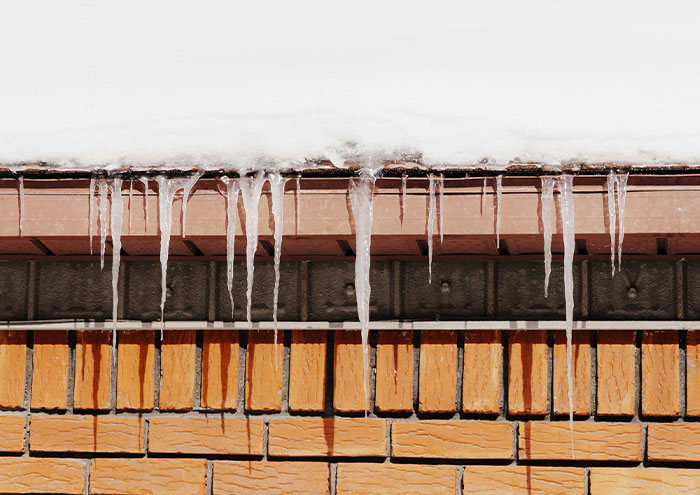 Icicles hanging from rooftop in cold winter scene representing passing away chill