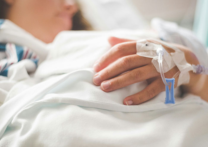 Closeup of patient hand with IV drip in hospital bed during passing away experience