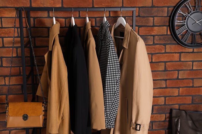 Coats and a purse on a rack against a brick wall, embodying expensive habits that save you money.