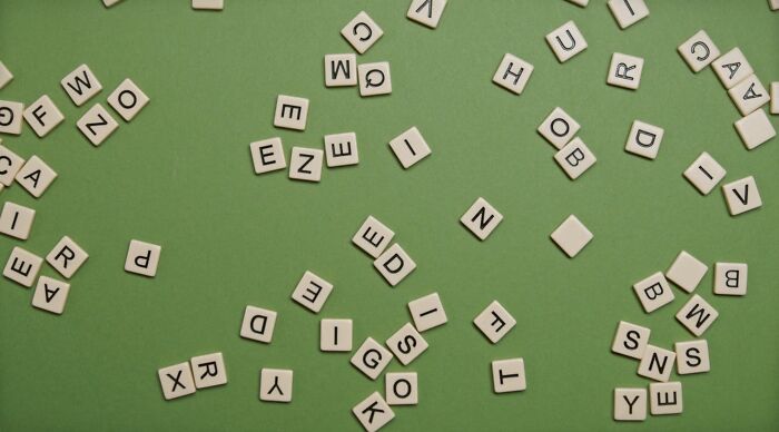 Scattered letter tiles on green background for pop culture rebus puzzle Scattered letter tiles on green background for pop culture rebus puzzle