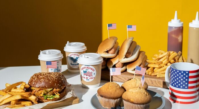 Everyday American quiz food featuring hot dogs, fries, cupcakes, coffee cups, and a flag-themed mug Everyday American quiz food featuring hot dogs, fries, cupcakes, coffee cups, and a flag-themed mug