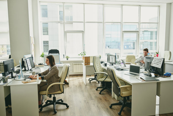 Coworkers in an office setting. A woman works at her desk. Potential for a lunch date invite.