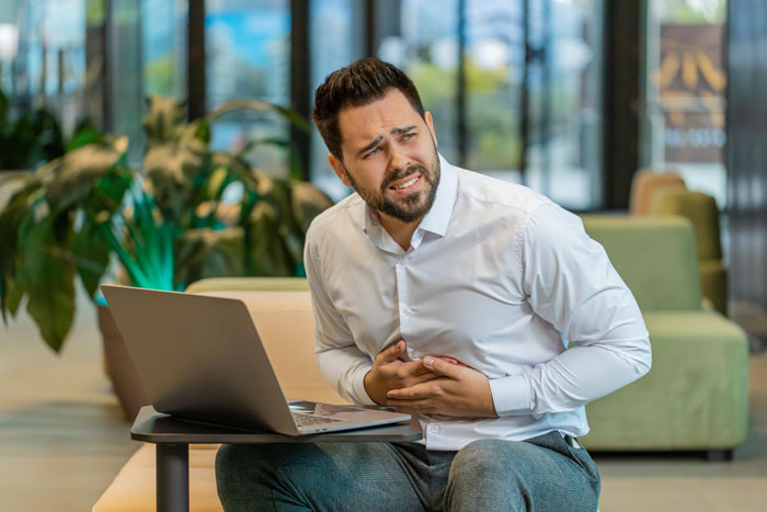 A man in an office, clutching his stomach in pain after eating Ghost Pepper Chili. He's an Office Food Thief speeding up his own firing. A man in an office, clutching his stomach in pain after eating Ghost Pepper Chili. He's an Office Food Thief speeding up his own firing.