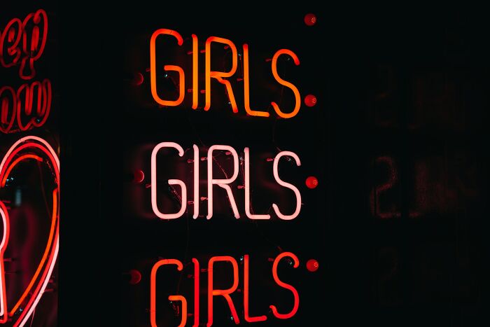 Neon sign displaying girls in red and pink glowing letters