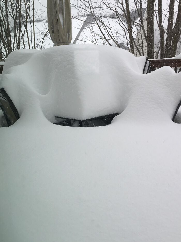 Rare heavy snow covers outdoor chairs completely with thick snow blanket