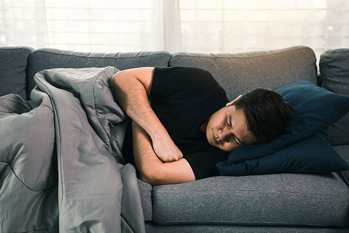 Man sleeping on couch under blanket feeling uneasy about creepy things women have done