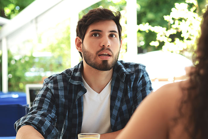 Surprised man in conversation outdoors, reacting to creepy things women have done