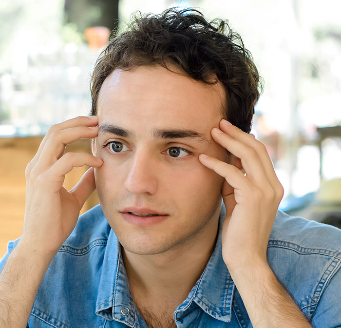 Worried man with hands on temples recalling creepy things women have done to men