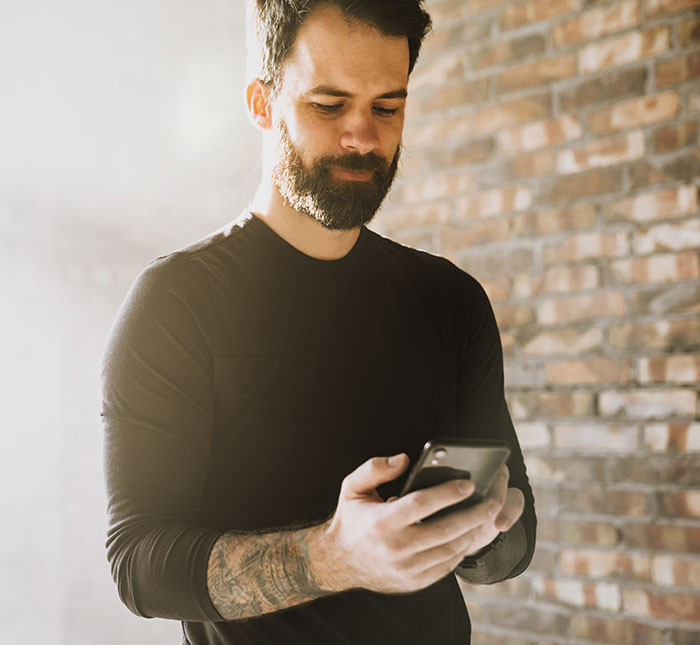 Bearded man checking phone text about creepy things women have done to men