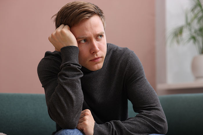 Pensive man sitting with head resting on hand thinking about creepy encounters