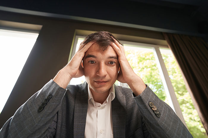 Frustrated man with hands on head sharing creepy experiences