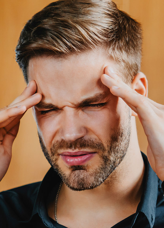 Man with headache touching temples, symbolizing stress from creepy experiences with women