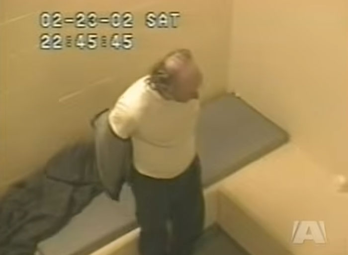 Surveillance image of a serial killer removing a jacket in a cell