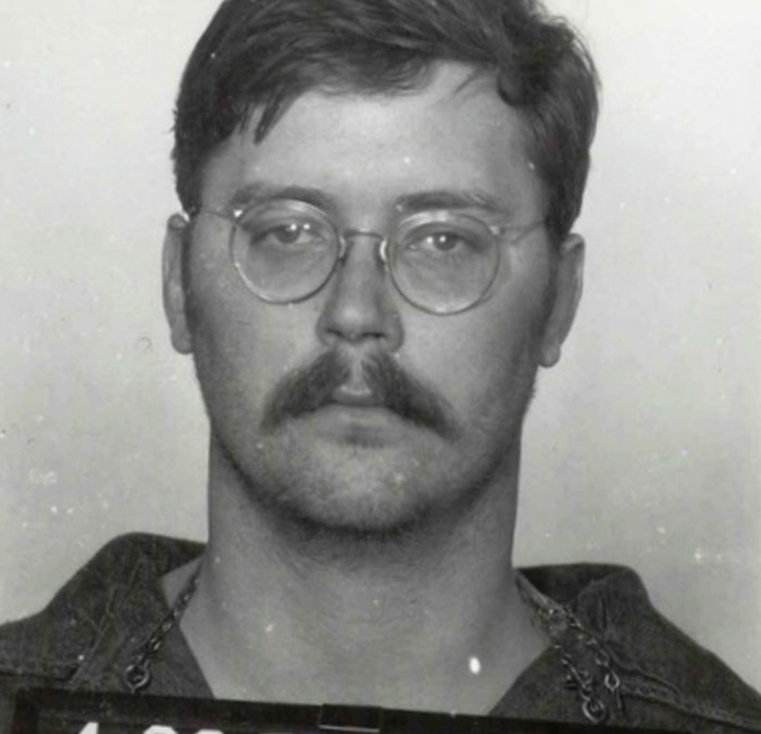 Black and white mugshot of a man with glasses and mustache serial killers facts