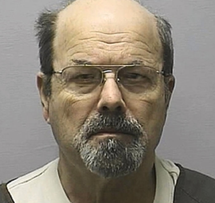 Mugshot of middle-aged serial killer with glasses and beard
