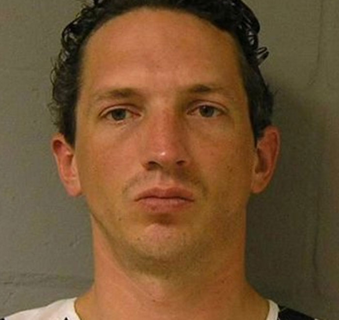 Color mugshot of young male serial killer with short curly hair