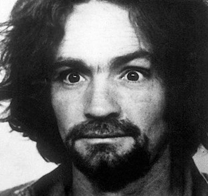 Black and white mugshot of serial killer with intense expression and beard