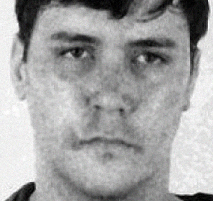 Black and white close-up mugshot of young male serial killer