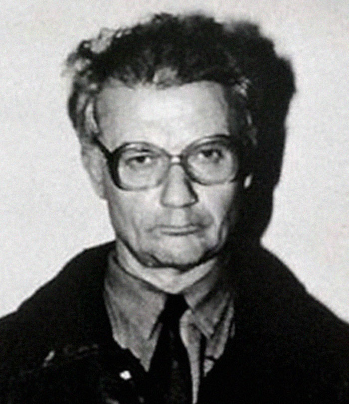 Vintage black and white photo of a serious looking serial killer with glasses
