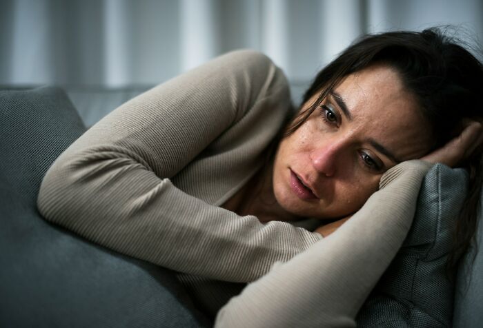 A woman lying on a couch with a sad expression, illustrating the emotional toll of wedding drama stories.