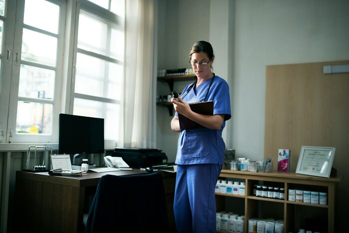A doctor in blue scrubs and glasses stands in an office, reviewing a chart. Like an epic comeback, she's ready.