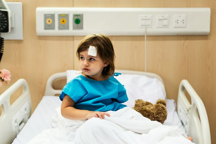 A young child in a hospital bed with a bandage on their forehead, contemplating deeply immoral situations.