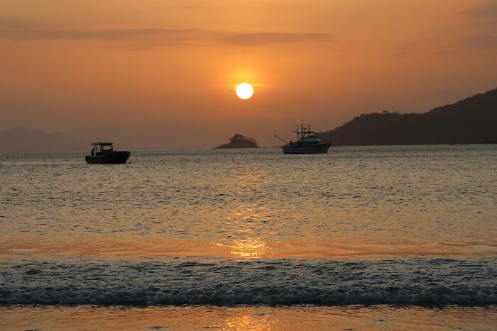 Sunset over ocean with boats highlighting absurd geography facts
