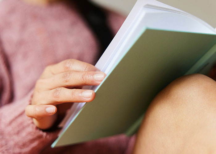 Person reading book exploring dark secrets accidentally discovered