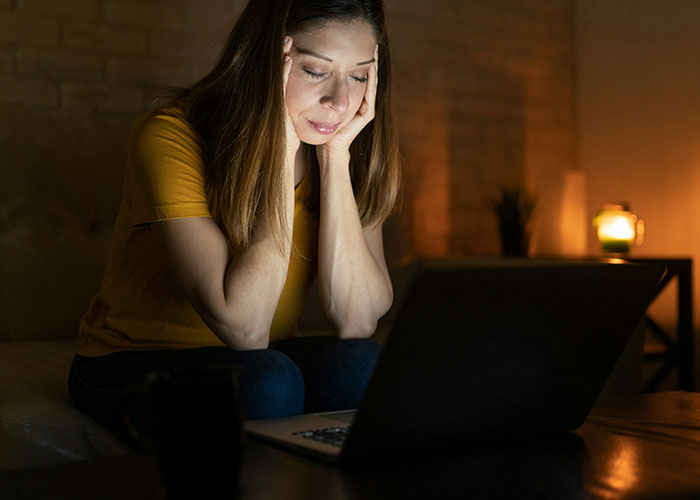 Worried woman at laptop late at night discovering dark secrets