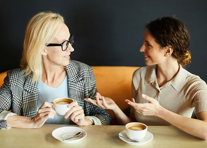 Two women chatting over coffee sharing secrets accidentally discovered