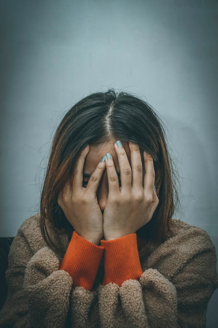 Young woman covering her face with hands in emotional distress
