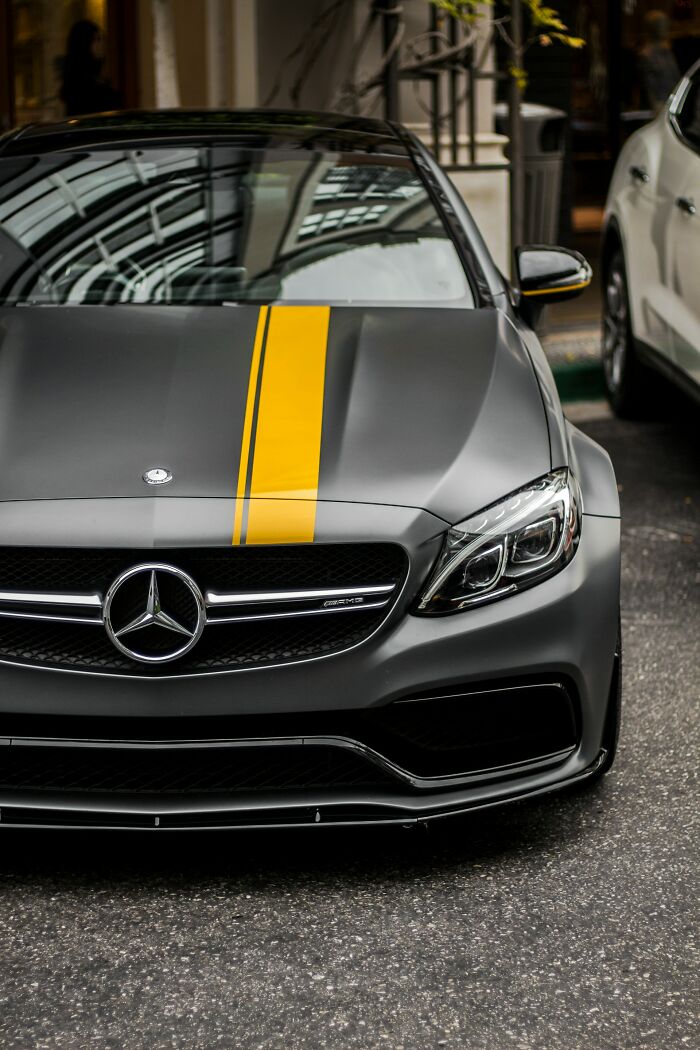 Matte black Mercedes car with yellow racing stripe parked