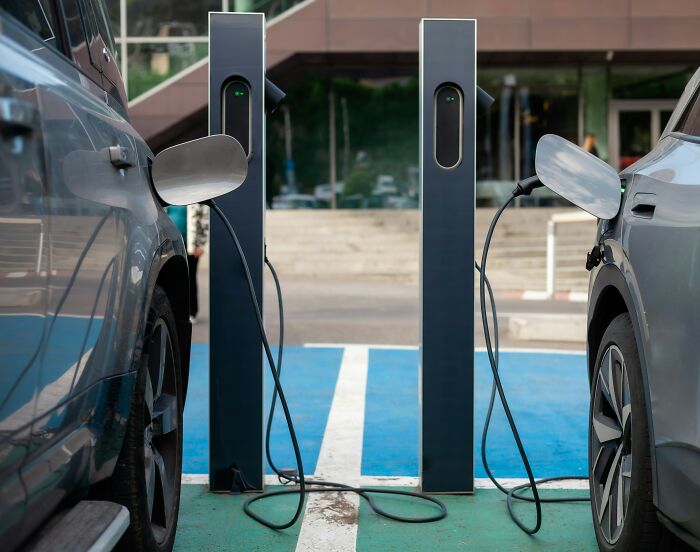 Two electric cars charging at outdoor stations, a habit that might actually save you money.