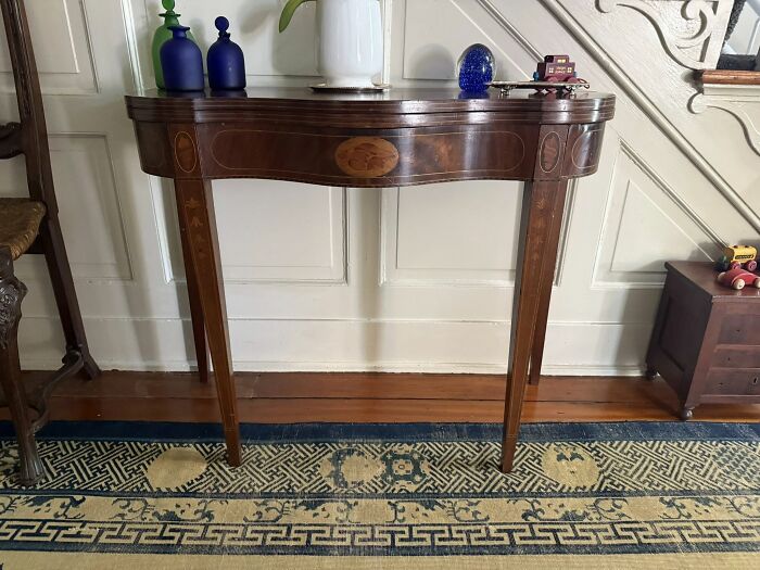 Ornate historic Early America antique wooden table with colorful vases and small collectibles, showcasing early American pieces.