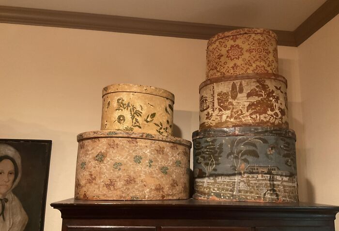 Early America historic pieces: stacked oval boxes with painted designs, showcasing various collected patterns and scenes.