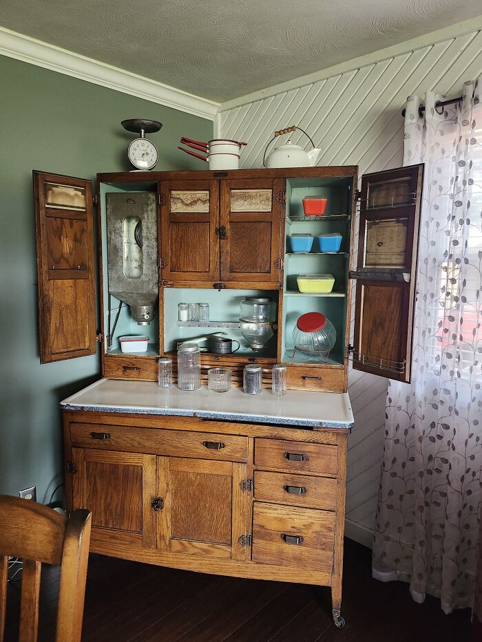 A classic Hoosier cabinet, an early American historic piece, filled with various kitchen collectibles and vintage items.