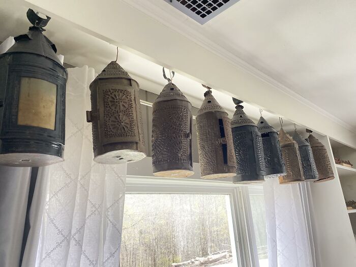 A collection of early American lanterns hanging above a window, showcasing historic pieces that people collected.