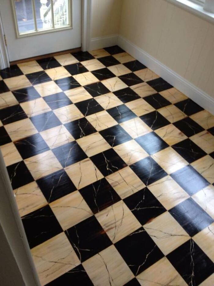 A black and tan checkered floor with visible wood grain, extending from a doorway. Historic pieces of Early America inspire this design.