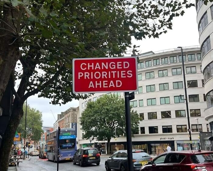 Red road sign indicating changed priorities ahead in UK city street