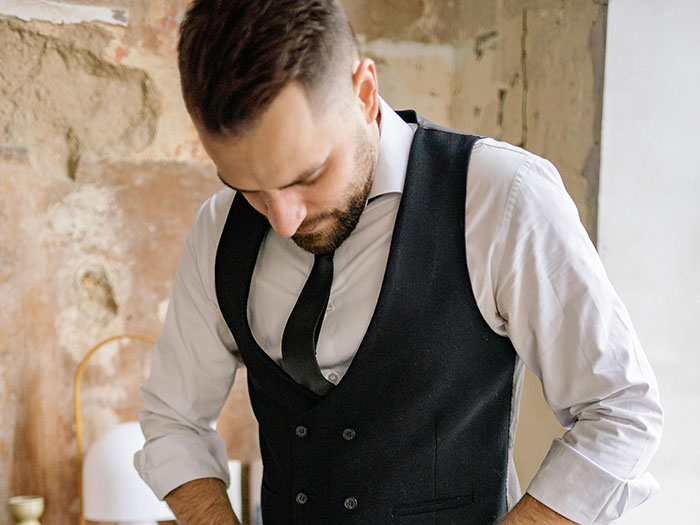 Man in vest and tie looking down in restaurant setting Man in vest and tie looking down in restaurant setting