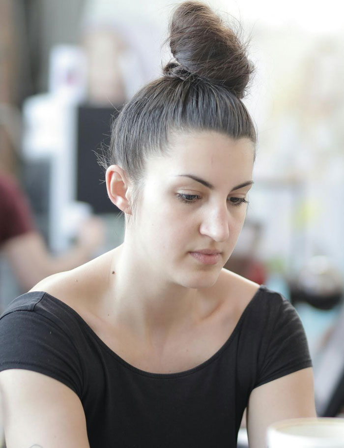 Woman with hair bun looking down, upset at restaurant Woman with hair bun looking down, upset at restaurant