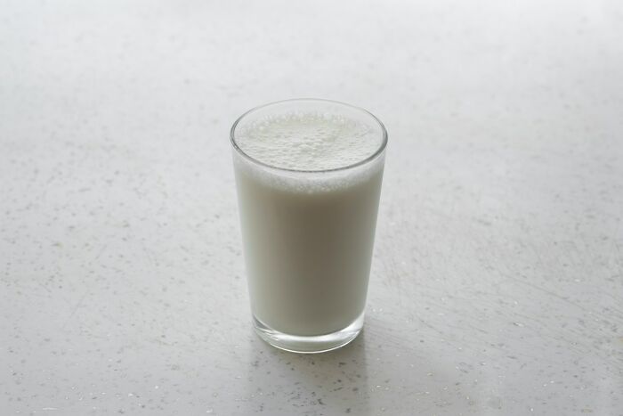 A glass of milk with frothy bubbles on top, on a speckled white surface, illustrating cool science facts.