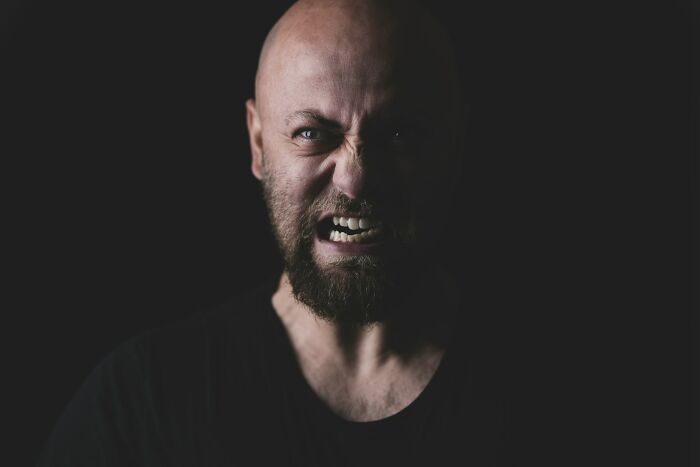 Angry bald man with beard in dark background showing frightening expression