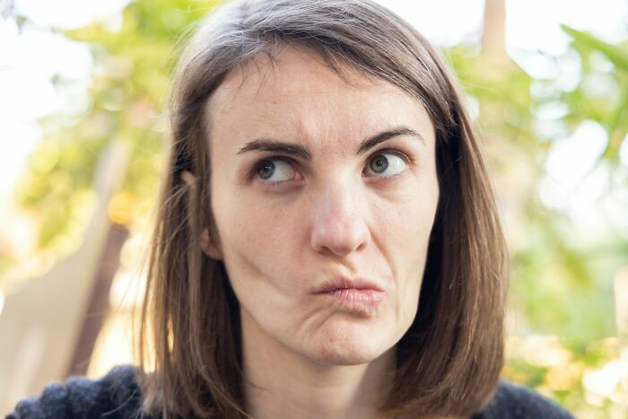 Woman making a skeptical face with blurred outdoor background